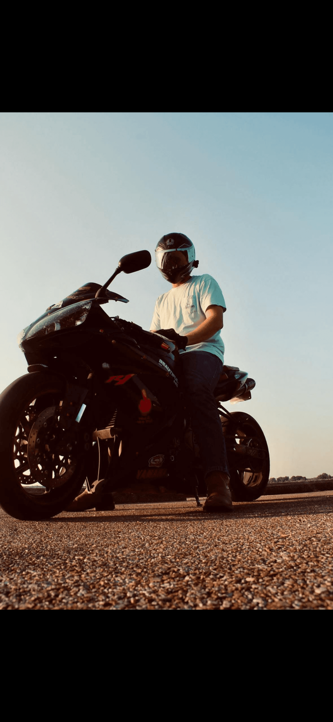 Person wearing a helmet sits on a black Yamaha sportbike on a paved road.